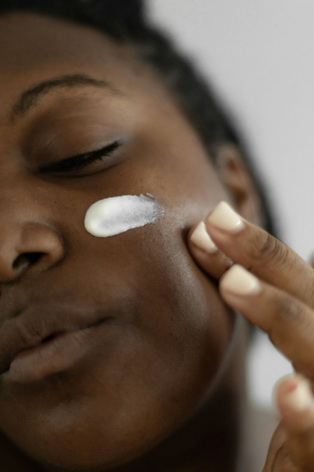 A woman smoothing lotion onto her cheek